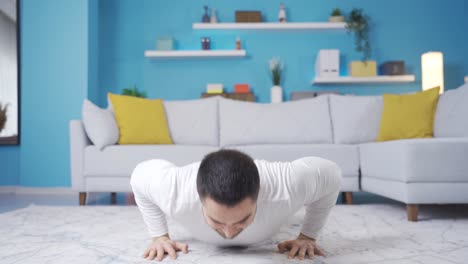 Joven-Haciendo-Flexiones-En-Casa-Mirando-A-La-Cámara,-Joven-Atleta-Mostrando-Cómo-Hacer-Flexiones.