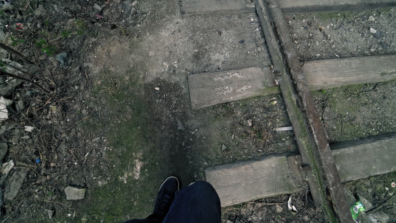 Legs of a man going on the path near the old railroad outdoors. Male's legs go through the dirty place with rubbish.