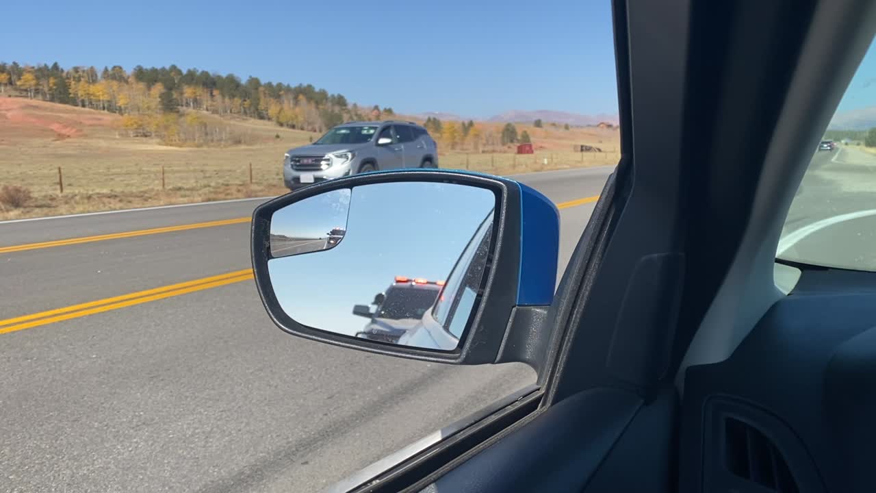 vista de un coche de policía en el espejo lateral con luces parpadeantes