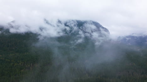 avión volando a través de las nubes hacia la cima de la montaña, paisaje canadiense