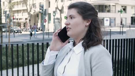 concentrated young manager talking on smartphone during stroll