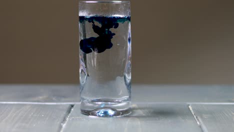 dejando caer gotas de colorante alimentario azul en un vaso de agua