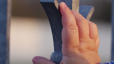 primer plano de un niño tocando una cerca de metal y sintiendo el material