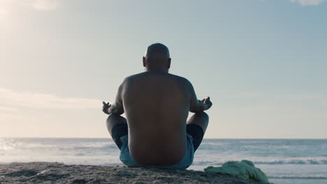hombre afroamericano meditando en la playa practicando la atención plena relajándose al aire libre disfrutando de la calma de la playa 4k