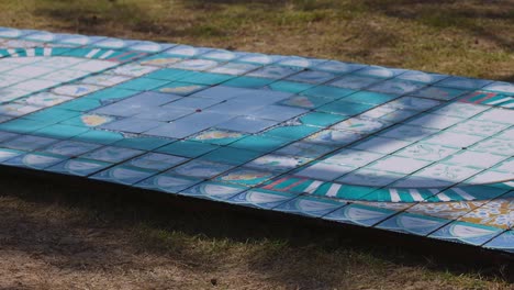 colorful tiled artwork displayed on grassy ground