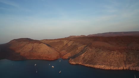 Toma-Aérea-De-Una-Ensenada-Al-Atardecer-Con-Botes-Y-Pequeñas-Playas-En-La-Isla-Partida,-Parque-Nacional-Archipiélago-Espritu-Santo,-Baja-California-Sur