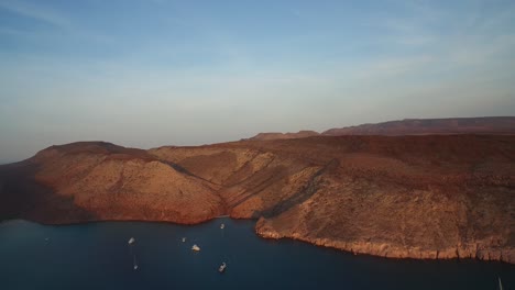 toma aérea de una ensenada al atardecer con botes y pequeñas playas en la isla partida, parque nacional archipiélago espritu santo, baja california sur