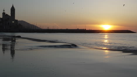 coastal sunset time-lapse captures tranquil reflection of church as sea gently washes ashore against backdrop of serene blue morning skyline