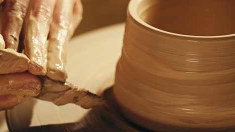 hands shaping clay on a pottery wheel