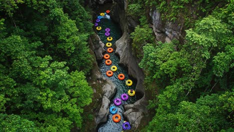 an aerial view of a scenic river meandering through lush greenery, highlighted by colorful inflatable tubes floating along its serene waters