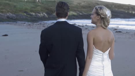 smiling newlyweds walking on the beach