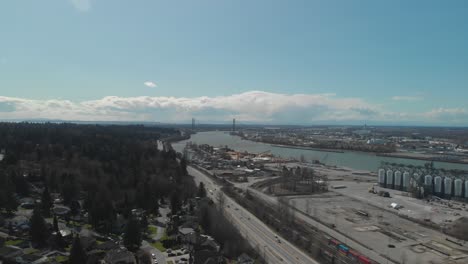 trucks cars traffic travelling along south perimeter high delta bc aerial wide high above trucking right moving vehicles below day blue sky clouds bridge in background