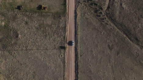 Drone-shot-of-car-driving-on-dirt-road-in-Willcox,-Arizona,-epic-downward-angle-aerial-shot