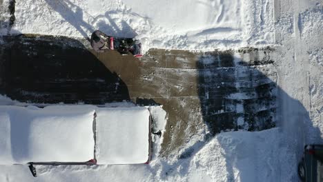 aerial top view of man using snow blower on driveway