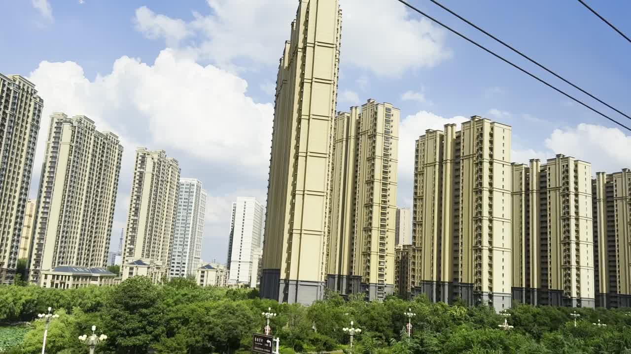 Scenic train ride in China, showcasing towering apartments with lush greenery in the foreground