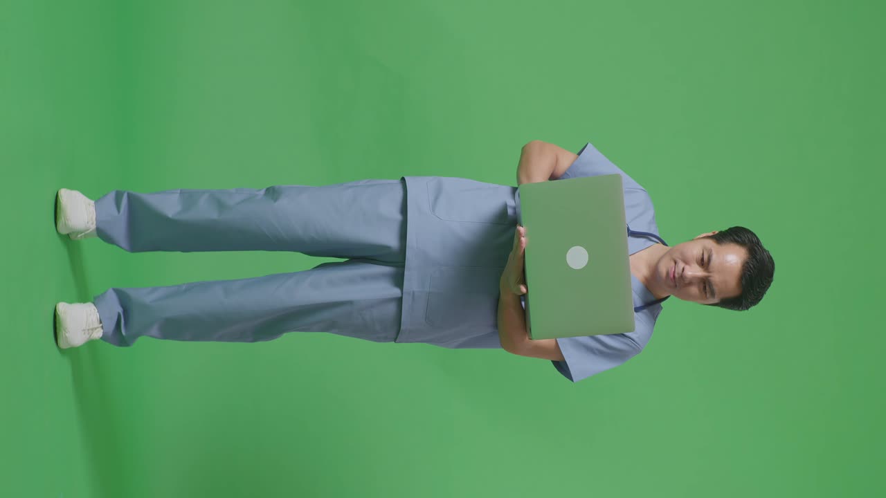 cuerpo lleno de médico masculino asiático con estetoscopio escribiendo en una computadora portátil en el fondo de la pantalla verde en el hospital