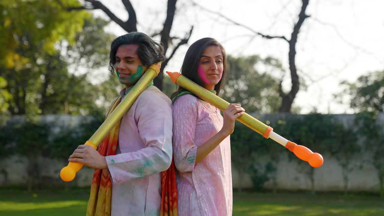 Sødt indisk par poserer med en vandpistol under Holi-festivalen.