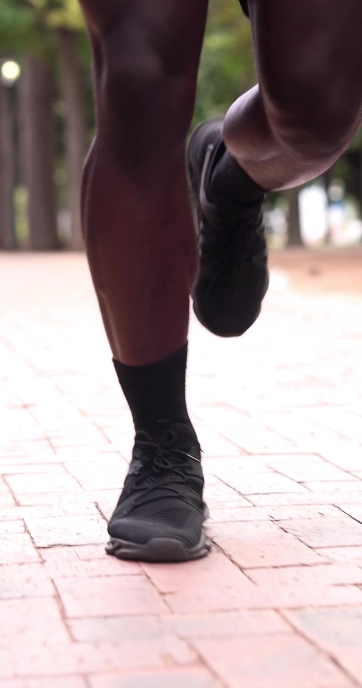 Close-up of a Runner's Legs Jogging on a Brick Path