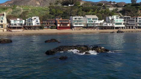 aerial shot of seals basking in the sun over a rock close to the shoreline in carbon beach,malibu, california, usa at daytime