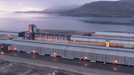 industrial building on shore of scenic fjord during cloudy morning, aerial