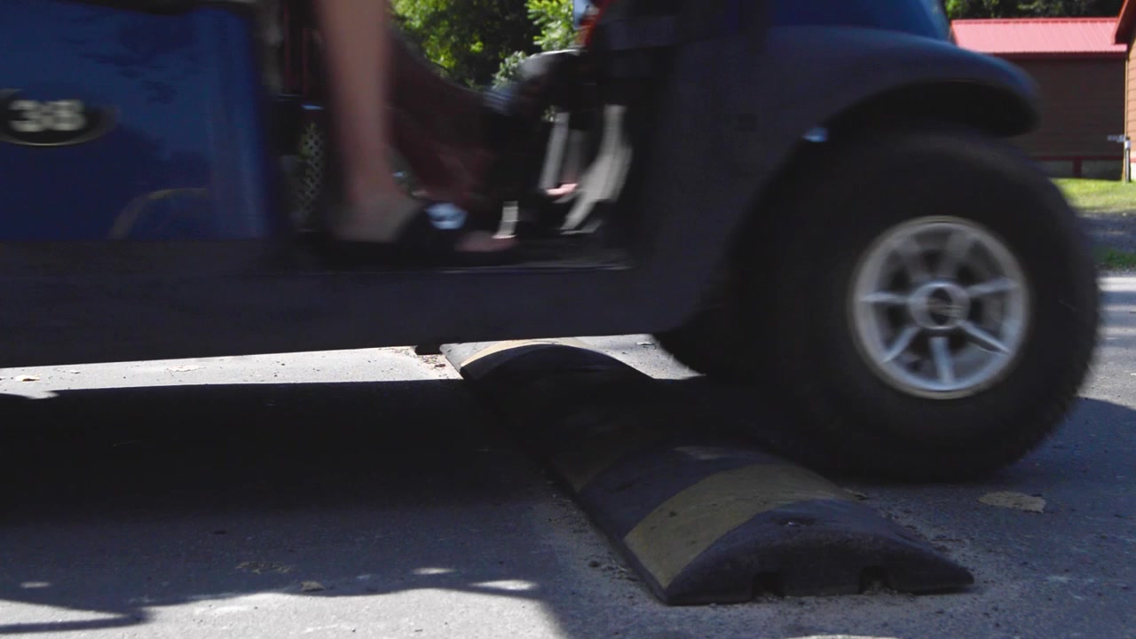 Golf cart drives over a ​speed bump
