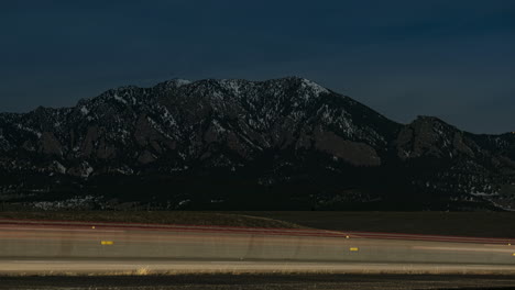 time lapse of cars driving by the flatirons near boulder, colorado at night time