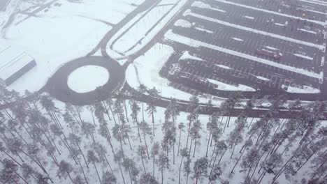 Almost-empty-parking-lot-near-forest-landscape-in-winter-season,-aerial-view