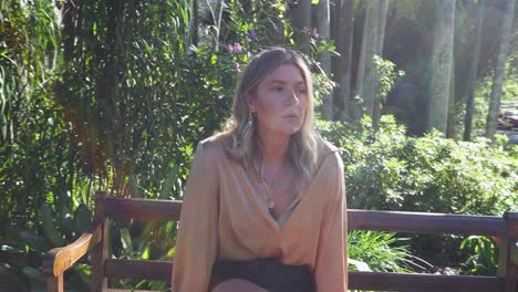 mujer joven sentada en un banco del parque en el jardín mirando alrededor_movimiento lento