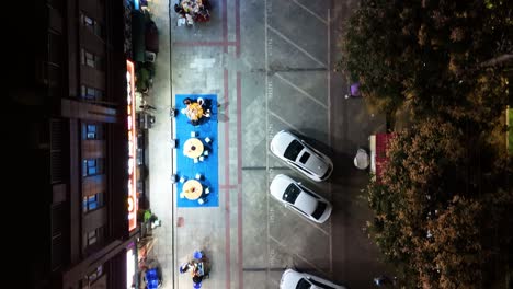 top-down aerial view of a street in shaanxi province, china, showing walkways, parking areas, and outdoor dining at restaurants with people enjoying meals, capturing the vibrant urban night scene.