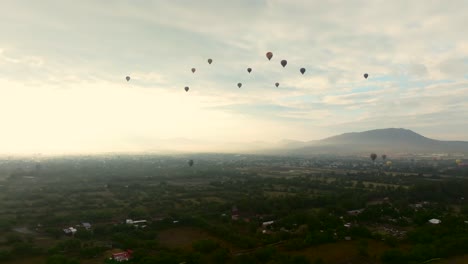 hot air balloons flying atop lush green park around teotihuacan, mexico. dolly in, ascending drone aerial