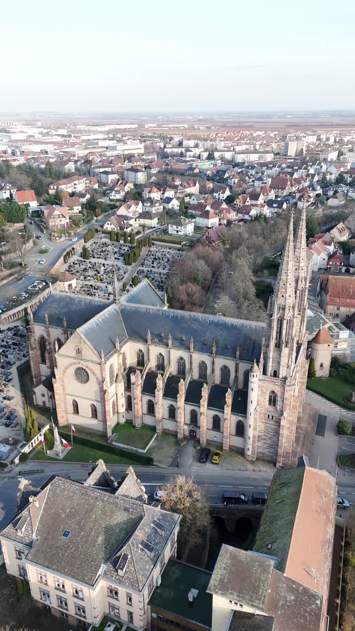 Saint Peter and Saint Paul's church in Obernai, France, aerial town architecture in vertical drone view