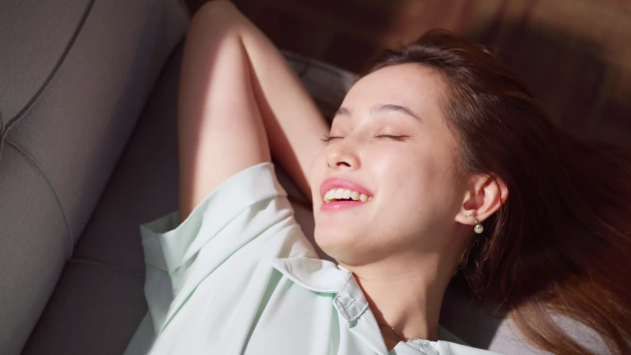 A woman enjoys a peaceful afternoon embodying relaxation and joy in a serene indoor setting.