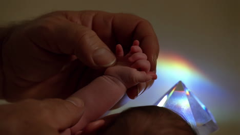 newborn baby hand being held with a prism reflecting light
