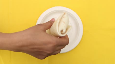 las mujeres recogen con la mano el envoltorio de pollo de un plato ,