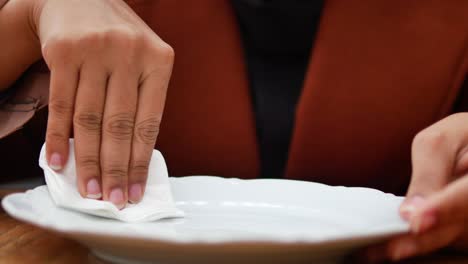 mujer limpiando un plato blanco con una servilleta