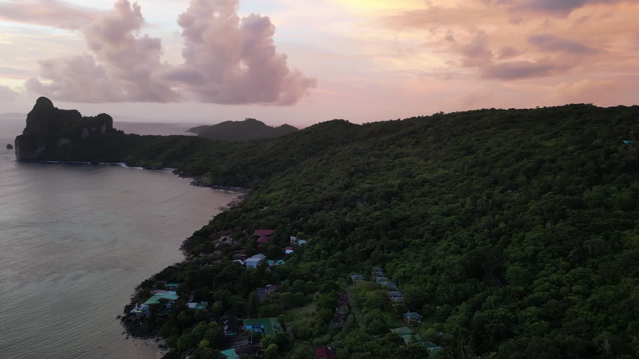 A partial aerial orbit capturing the serene forest on Koh Phi Phi, Thailand, bathed in the warm hues of sunset.