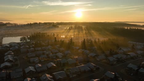 wide establishing aerial view of a sunrise shining through morning fog above a suburban neighborhood