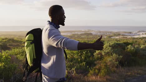 Afroamerikanischer-Mann-Mit-Rucksack,-Der-Versucht,-Einen-Aufzug-Anzukuppeln,-Während-Er-Auf-Der-Straße-Steht