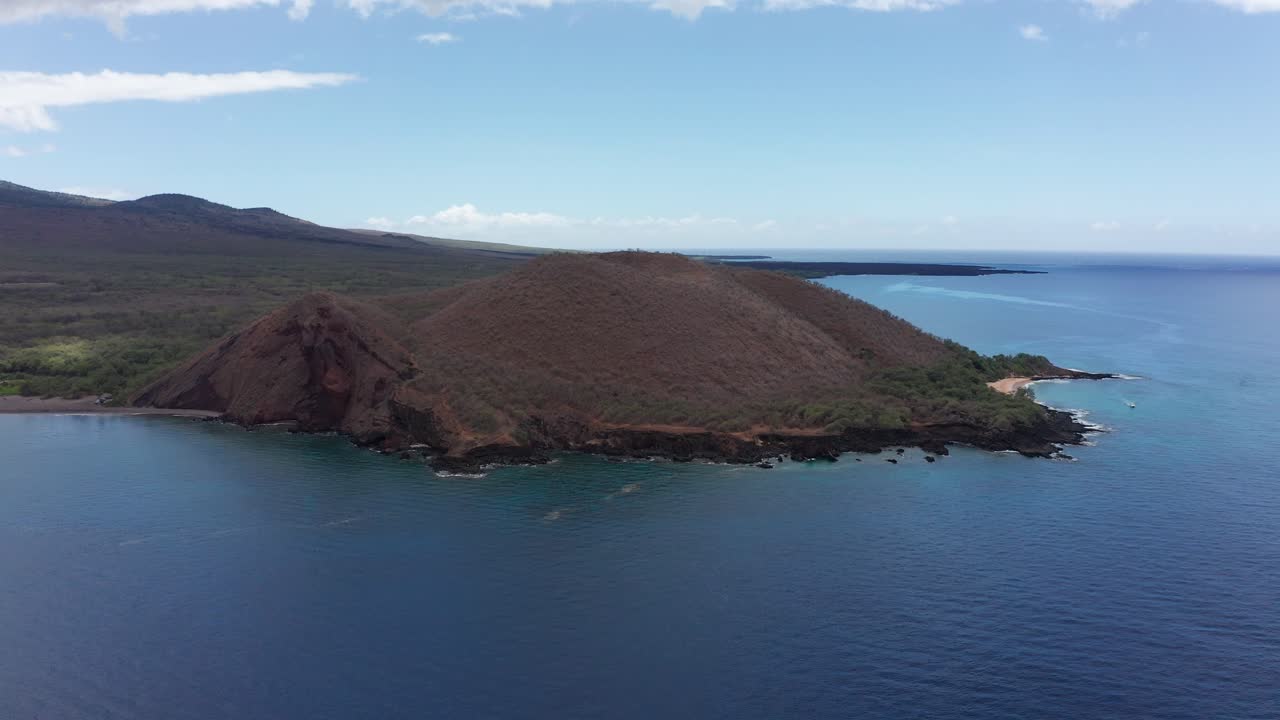 Descending aerial close-up shot of the volcanic cinder cone Pu'u Olai near Maluaka Beach on the southern coastline of Maui, Hawai'i