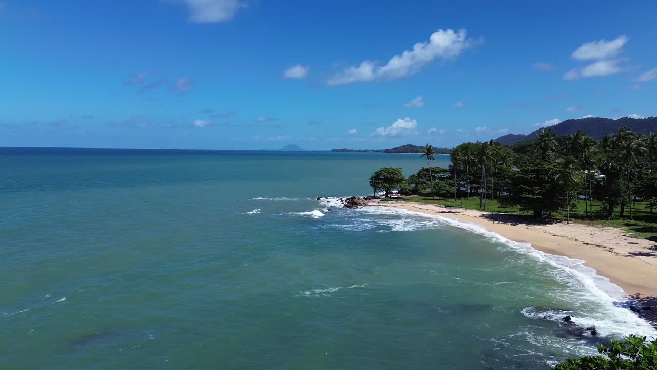 Cinematic aerial semi orbit around lush tropical rainforest on Koh Lanta, Thailand, gradually revealing a remote paradise beach with turquoise ocean water, white sand, and untouched coastal wilderness