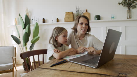 Mutter-Erklärt-Ihrer-Hübschen-Blonden-Tochter-Den-Unterricht-über-Den-Laptop-bildschirm