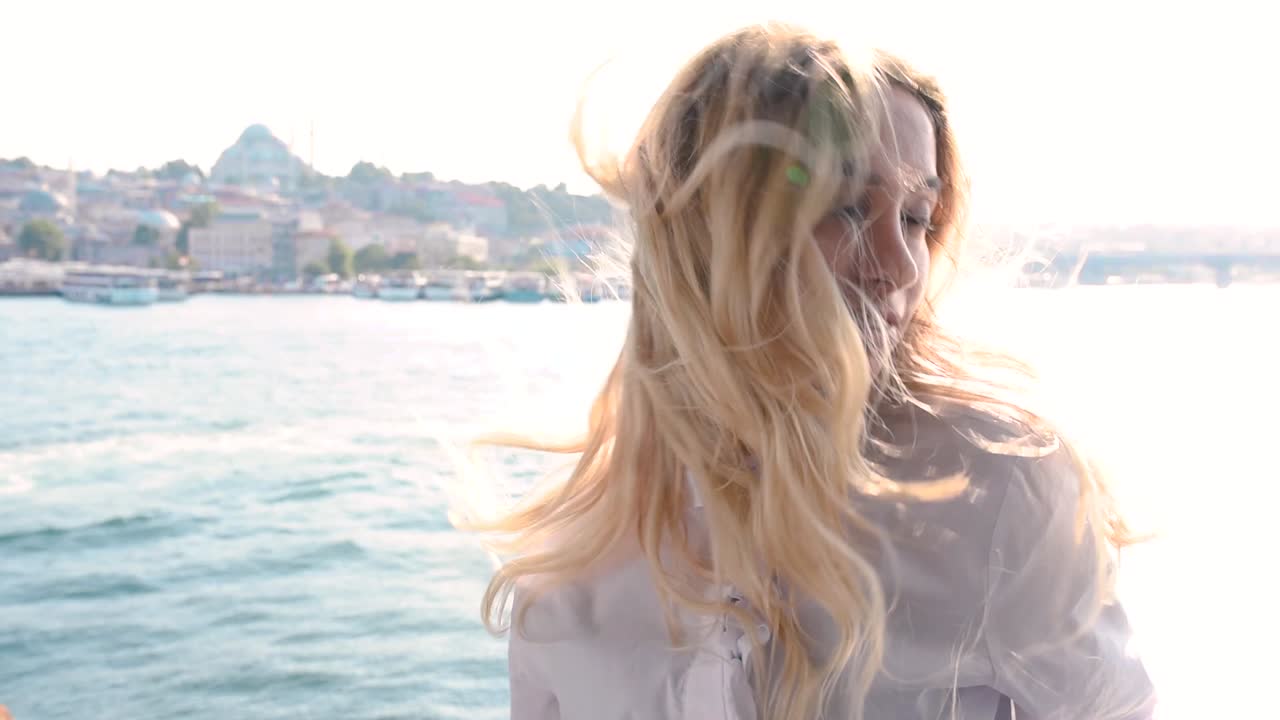 아름다운 소녀가 갈라타 다리 위에 포즈를 취하고 터키 이스탄불에 있는 보스포러스와 술레이마니예 모스크의 전망을 즐깁니다.