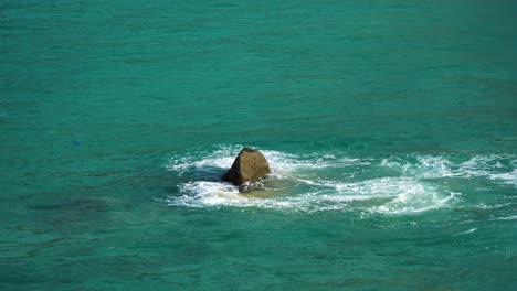 smooth sea wave splash through sharp rock, emerald seawater close up