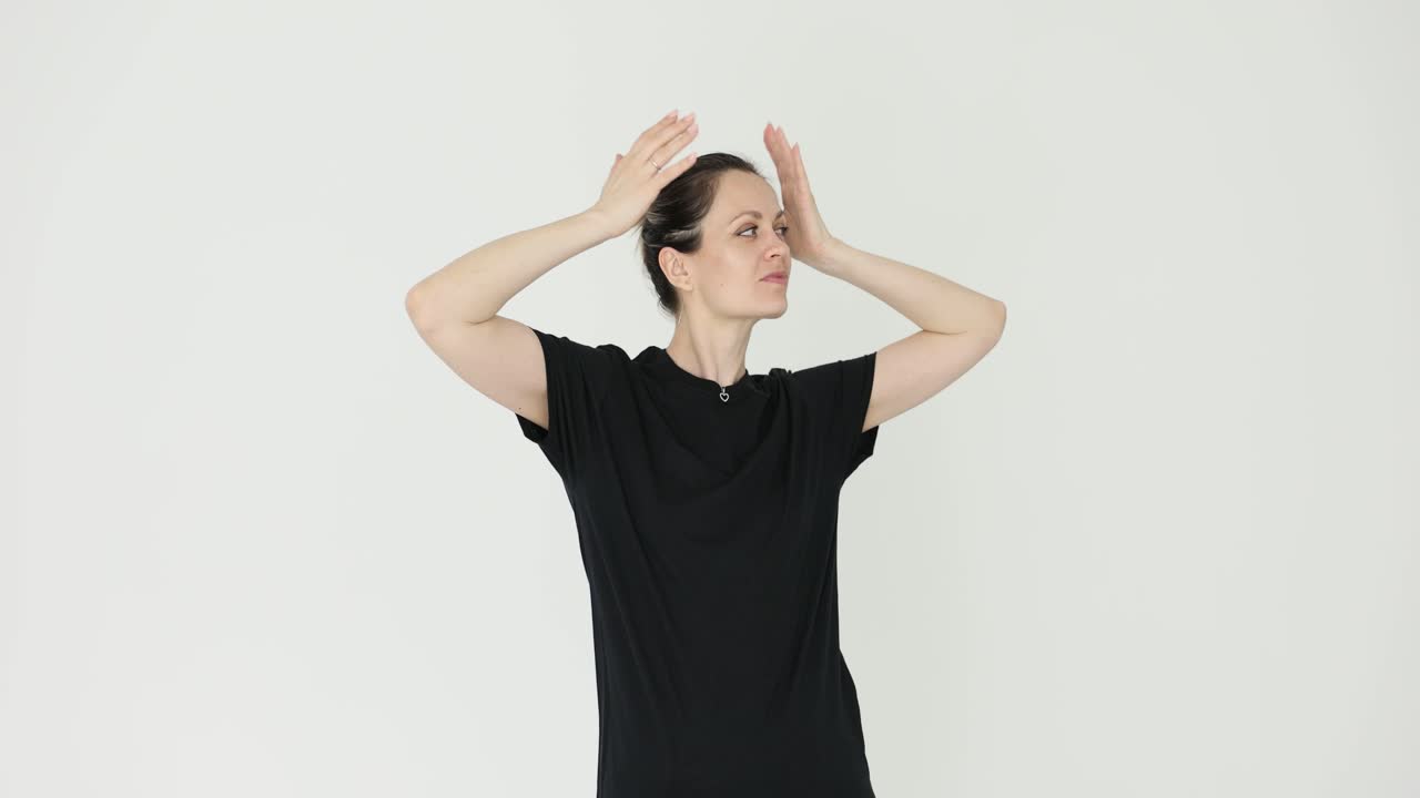 Woman adjusting her hair in a black t-shirt against a white background