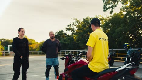 Un-Instructor-De-Conducción-Con-Una-Camiseta-Amarilla-Les-Dice-A-Un-Chico-Y-A-Una-Chica-Cómo-Sentarse-En-Una-Motocicleta.-Práctica-De-Conducción-Después-De-Estudiar-Teoría