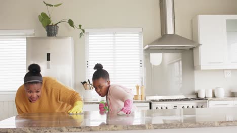 madre y hija afroamericanas felices limpiando la encimera en la cocina, cámara lenta, espacio de copia