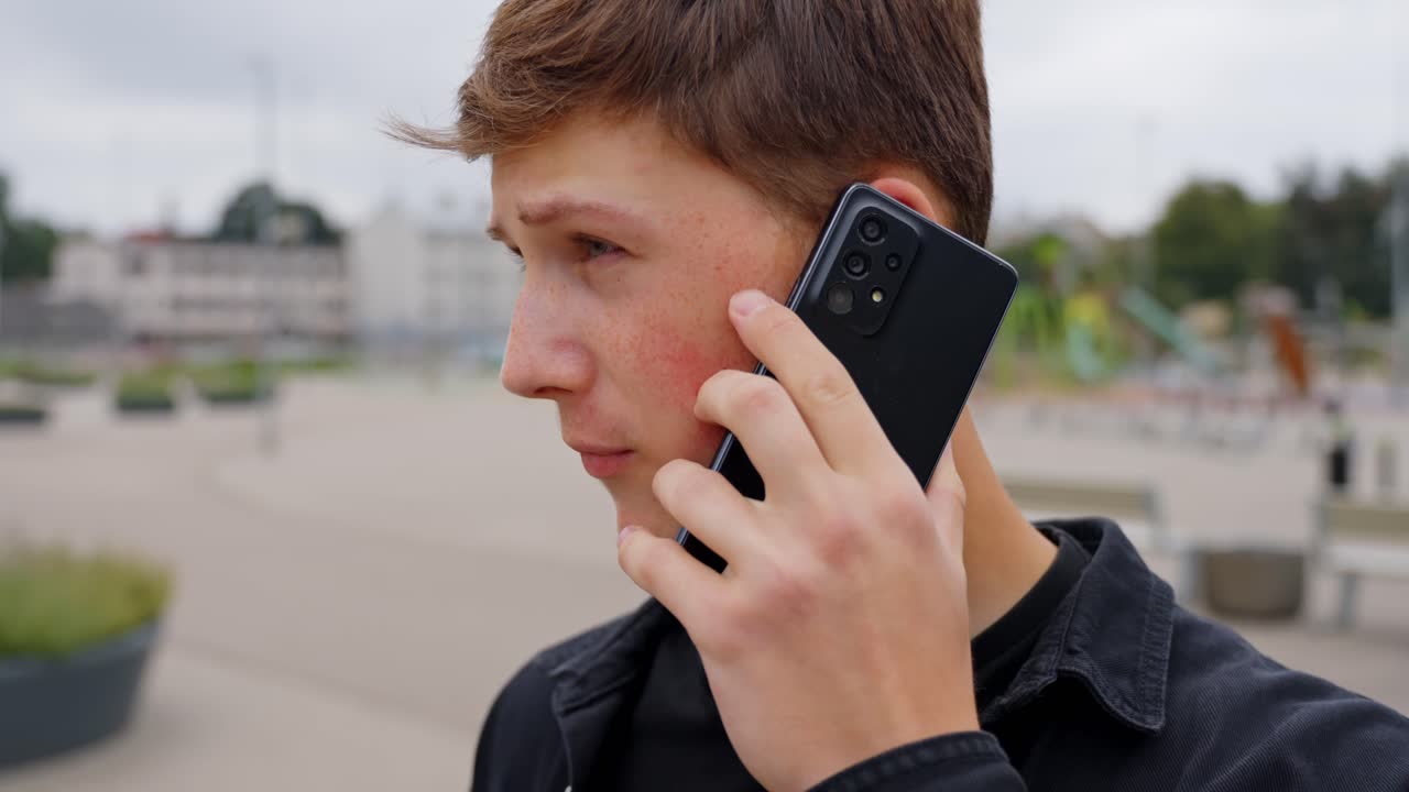 Young white man talks on phone with downcast eyes looking sad and dismayed in quiet moment