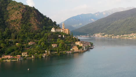 amplio y revelador disparo de dron de chiesa di santa maria del sasso en suiza volando sobre el lago de lugano