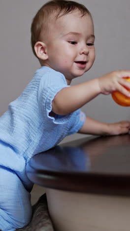 playful happy caucasian boy is busy with his toy. healthy child holding a ball and banging it by the stair. vertical video
