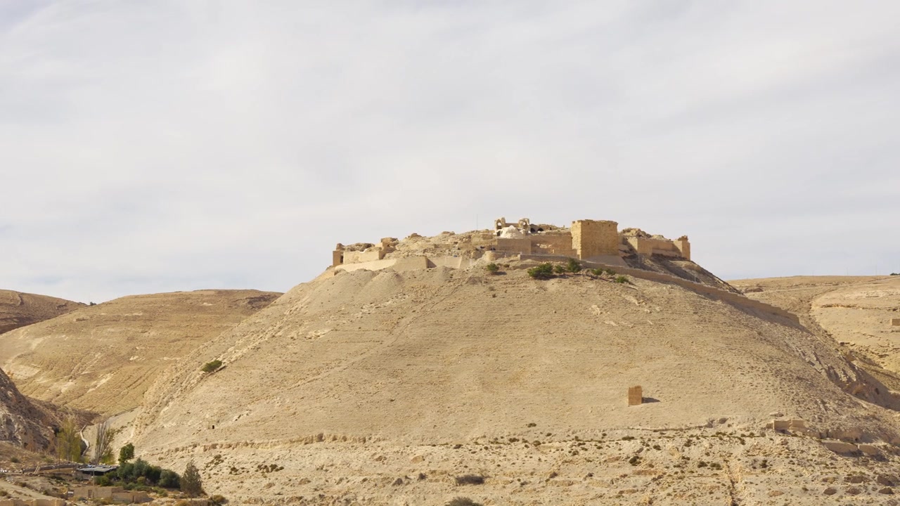 Ripresa panoramica di ambientazione, rovine del Castello di Shobak che coronano una collina arida vicino a Shobak, Giordania, con la fortezza crociata medievale che domina il paesaggio desertico aspro.